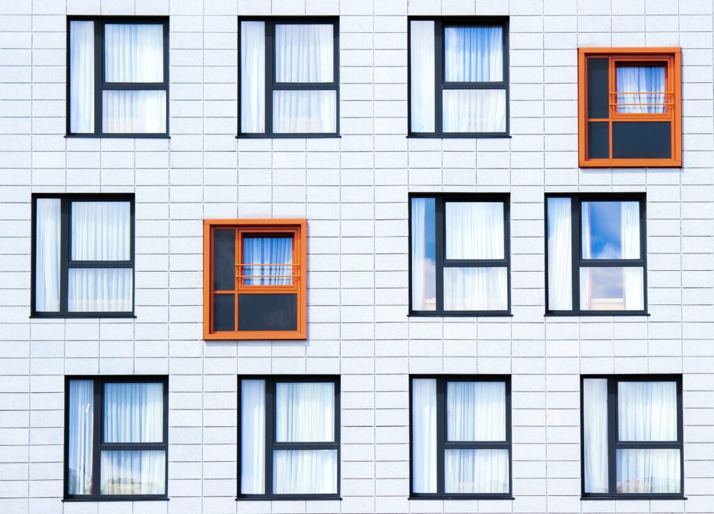 Fassadenreinigung Berlin &ndash; helle Hauswand mit schwarzen und orangefarbenen Fensterrahmen