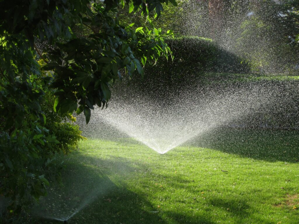 Gartenpflege Berlin &ndash; Rasensprenger bew&auml;ssert eine schattige Wiese