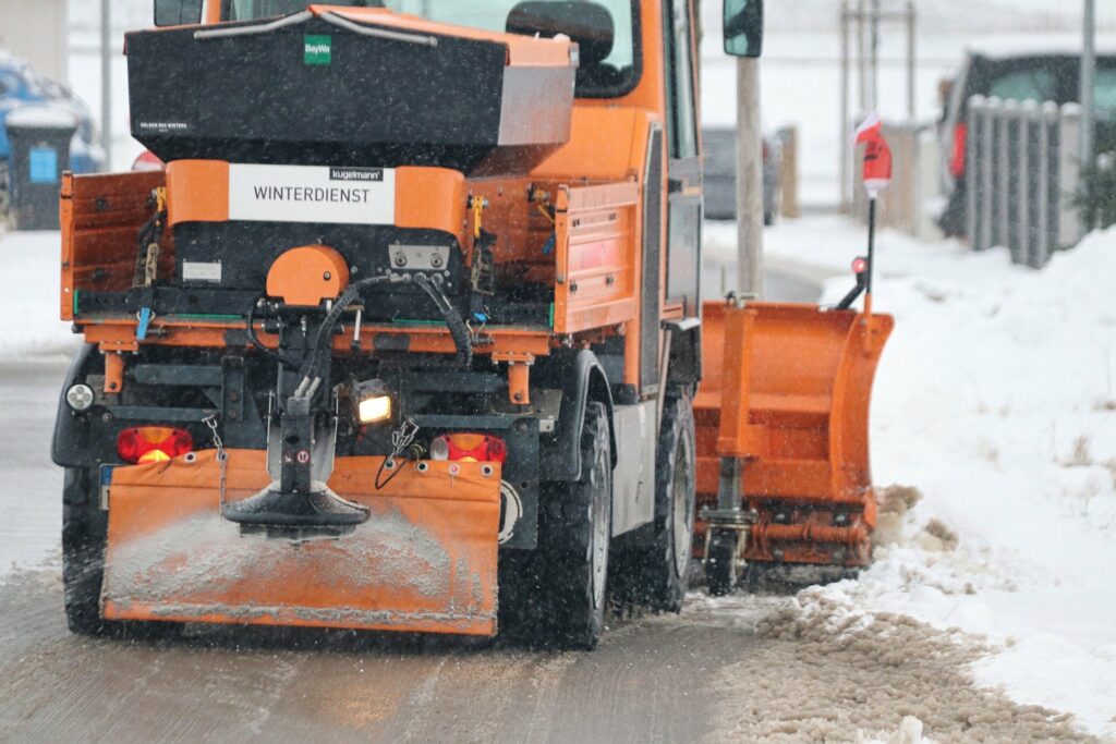 Winterdienst Berlin &ndash; R&auml;umfahrzeug mit Schneeschild und Streuer im Einsatz
