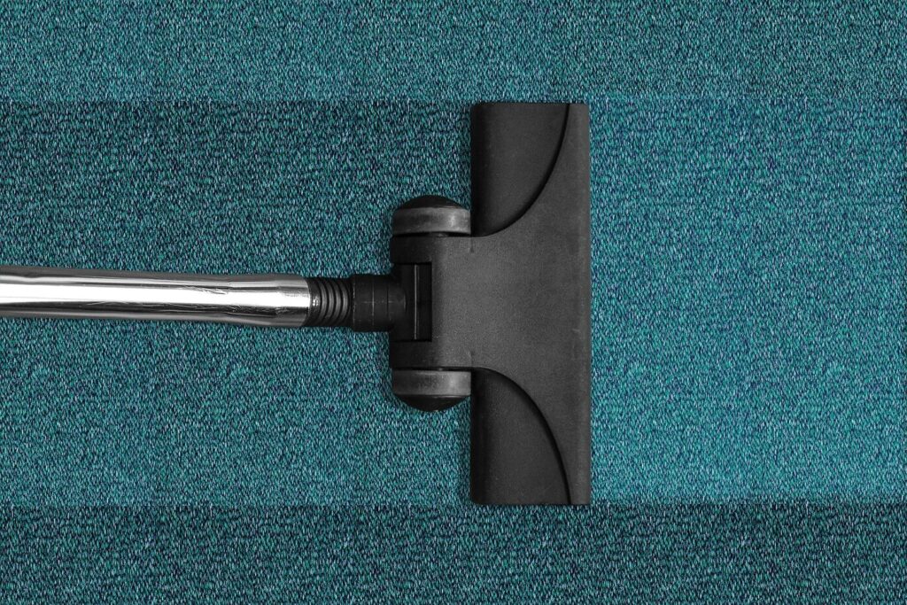 Reinigungskraft saugt den Teppichboden einer ger&auml;umten B&uuml;rofl&auml;che in Berlin nach dem Auszug