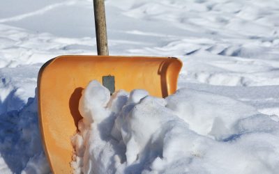 Winterdienst Berlin &ndash; orangefarbene Schneeschaufel steckt im frischen Schnee